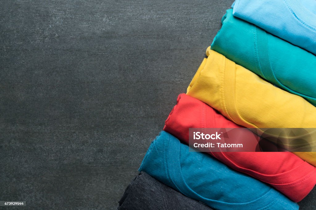 close up of rolled colorful clothes on black background T-Shirt Stock Photo