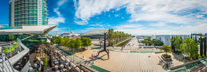 Locals and tourists enjoying the warm sunshine on the restaurants and terraces of the Parque das Nacoes, the modern waterfront development in Lisbon, Portugal’s vibrant capital city.