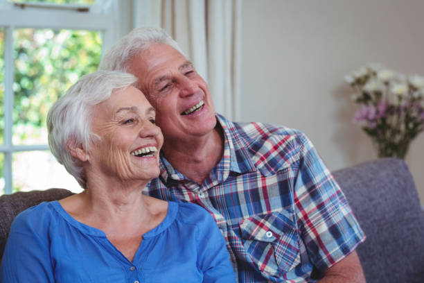istock Senior couple looking away while sitting on sofa 673935824