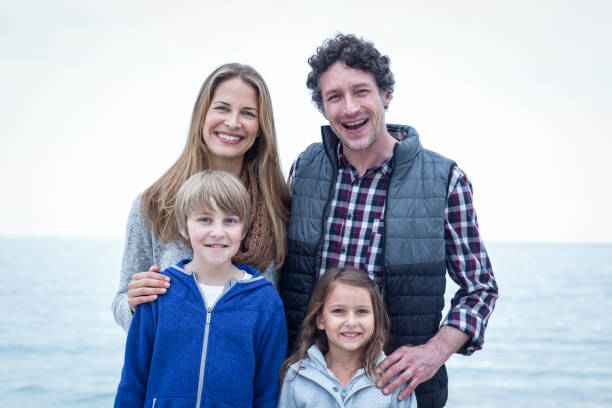 istock Cheerful family standing at sea shore 673937230