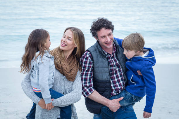 istock Parents carrying children while enjoying at beach 673937356