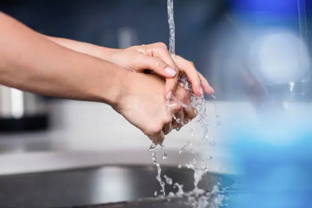 Cropped image of woman washing hands in kitchen at home