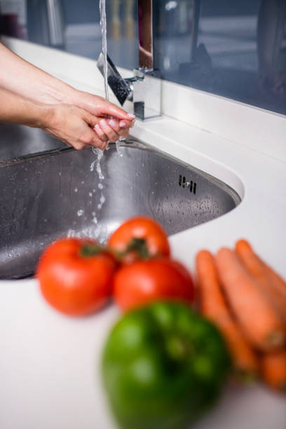 istock Woman washing hands in sink at kitchen counter 673940940