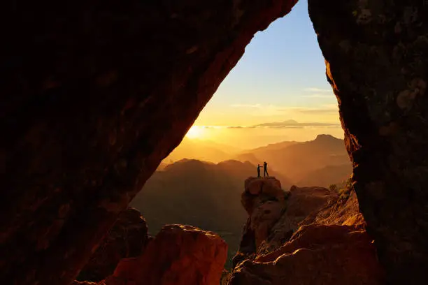 hikers in top of the mountain in the sunset admiring beautiful Grand Canary landscapes.photo taken from cave.