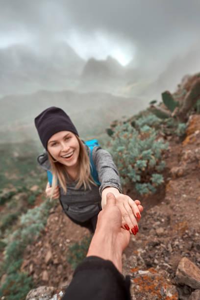 let me help you hiker woman smiling, climbing mountain, being helped by her friends.carrying her backpacker, photo taken in Tenerife. teno mountains photos stock pictures, royalty-free photos & images