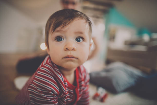 Portrait of a little baby boy posing for the camera while spending time with his parents in  living room