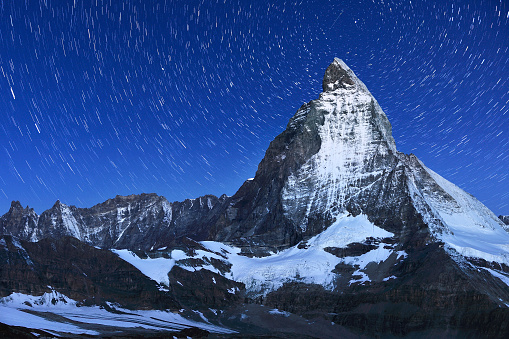 Swiss Alps's Matterhorn and star trail in midnight sky, Switzerland.