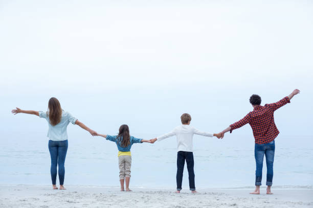 Family holding hands while standing at sea shore