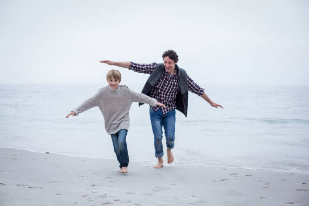 istock Father and son running on beach with arms outstretched 673965326