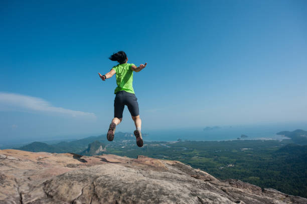 istock jumping on rocky mountain peak, freedom, risk, challenge, success concept 673971966