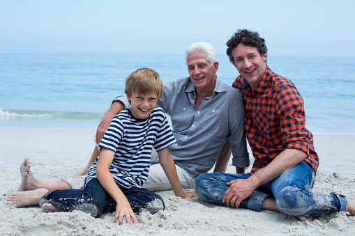Portrait of multi-generation family smiling while relaxing at sea shore