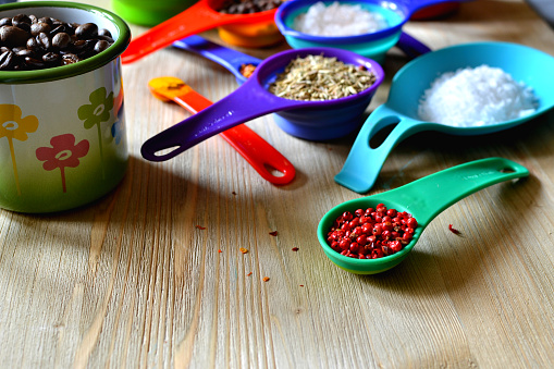 Spices, herbs, salt, sugar, coffee beans in bright colored measuring spoons and cups