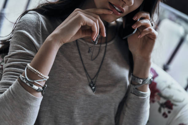 Close-up of young woman keeping hand on chin while talking on the smart phone