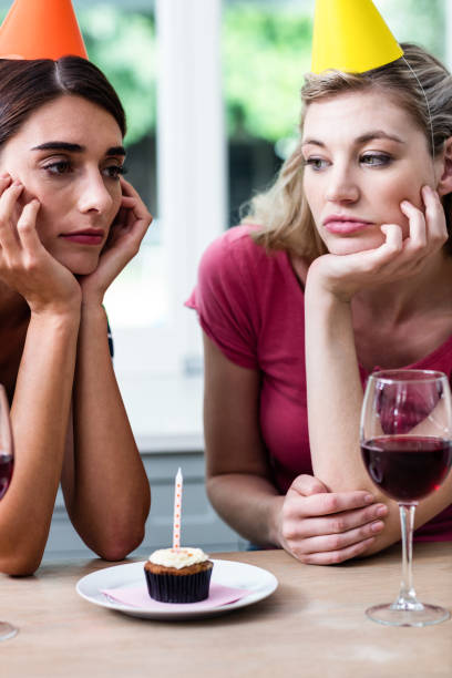 istock Sad friends sitting at table during birthday party 674016354