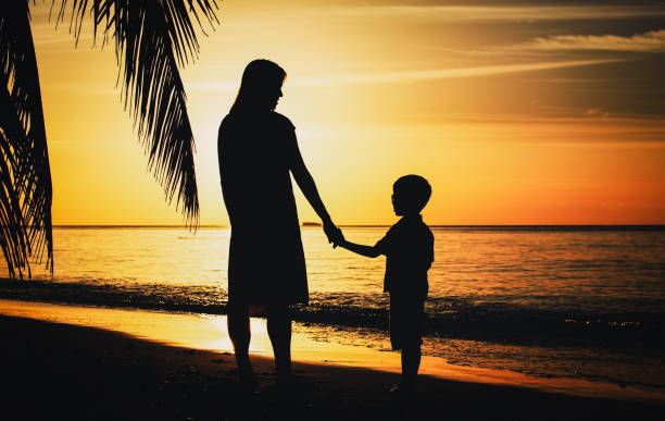 istock mother and son walking on sunset beach 674017880