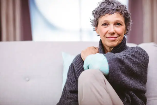 Photo of Portrait of smiling mature woman sitting on sofa