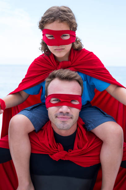 istock Confident father in superhero costume carrying son on shoulder 674030646