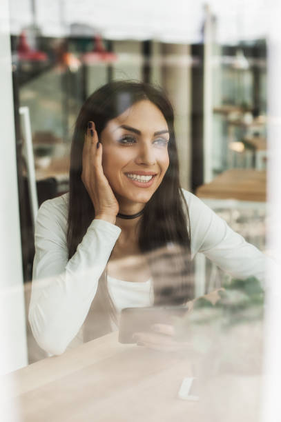 istock Happy woman having cell telephone conversation while sitting in cafe 674033242