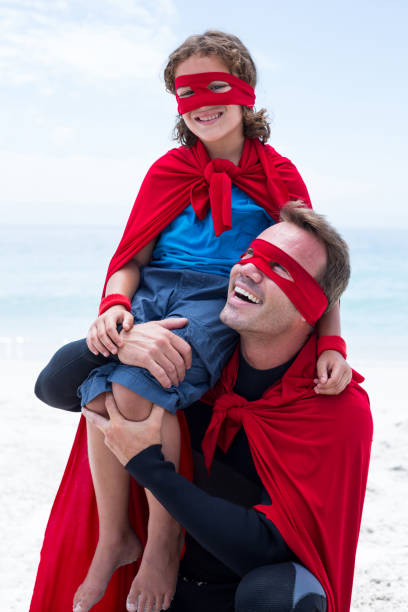 istock Father in superhero costume smiling while carrying son on shoulder 674033322
