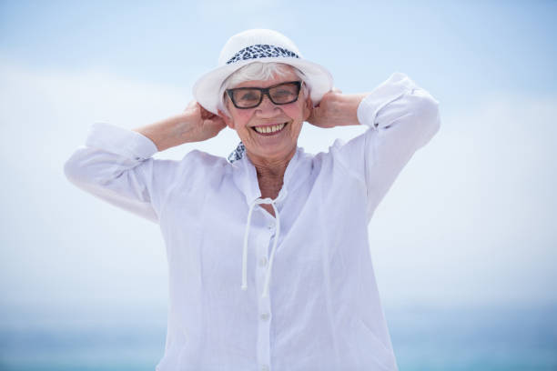Portrait of cheerful senior woman at beach against sky