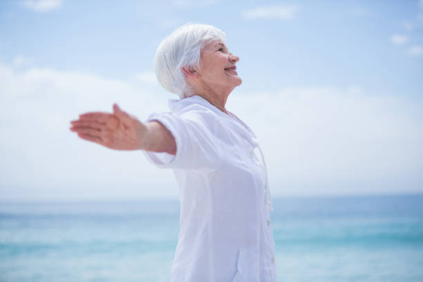 istock Senior woman smiling while exercising at beach 674034914