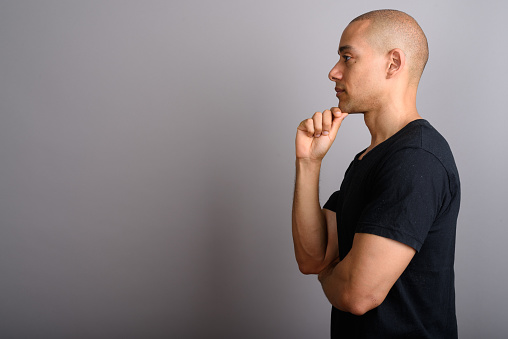 Studio shot of mature handsome bald man against gray background horizontal shot