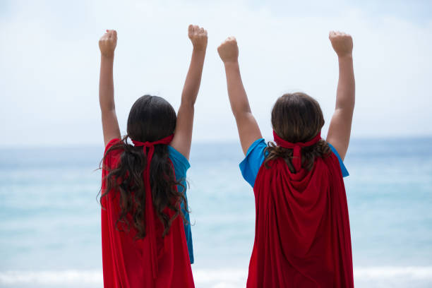 istock Siblings standing with arms raised at sea shore 674055088