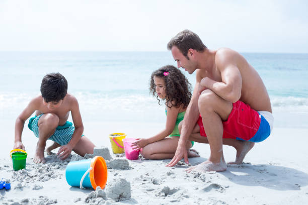 istock Father helping children building sand castle at beach 674062822