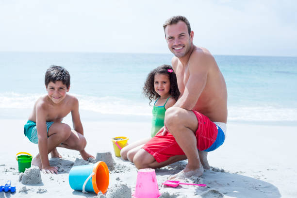 istock Smiling father playing with daughter and son at beach 674062970