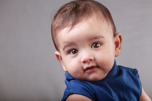 Portrait of a cute baby against gray background