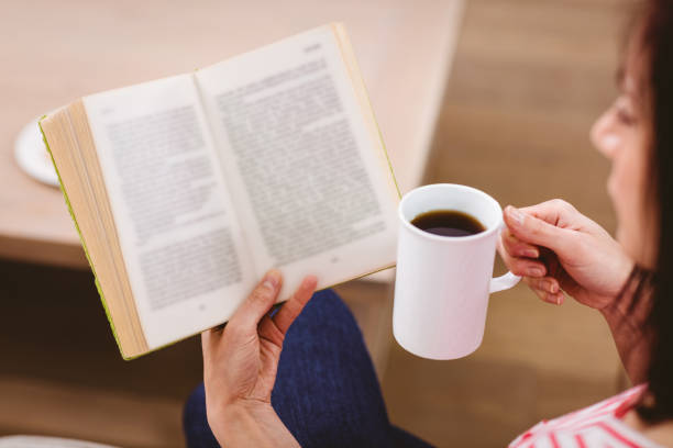 istock Cropped image of woman reading book while holding coffee cup 674083192