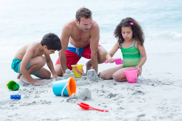 istock Father making sand castles with children at beach 674083520
