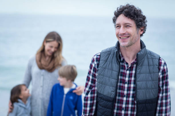 istock Father and mother standing with children at beach 674083912