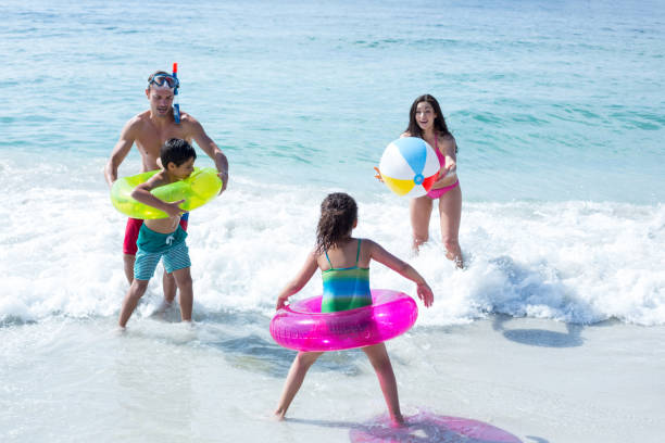 istock Happy family playing with beach ball at beach 674090618