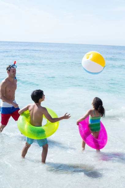 istock Father and children playing with ball on shore 674090858