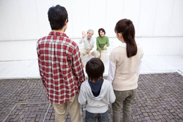 Son and his wife and grandchild waving senior couple