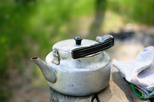A kettle on a wooden table. With a blurred background.