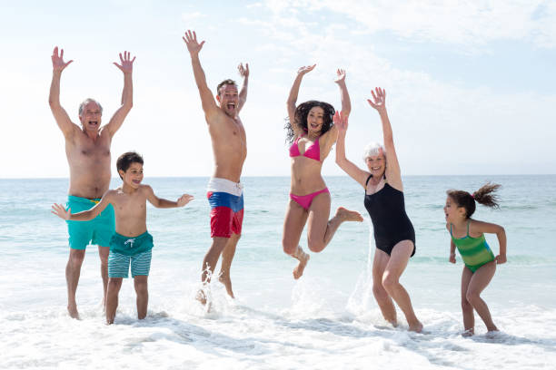 istock Happy multi genration family jumping at beach 674116116