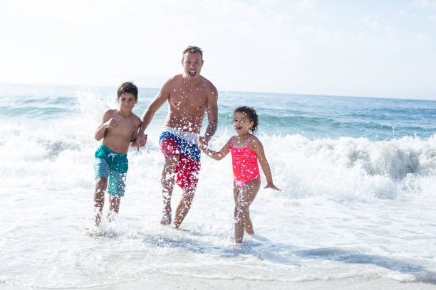 istock Father enjoying with children in shallow water 674121896
