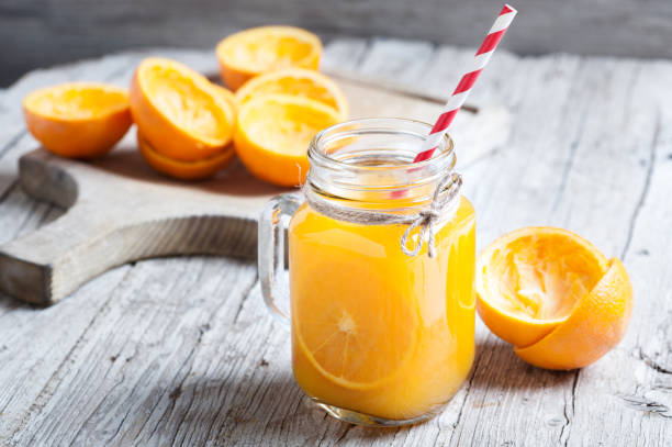 Orange Juice Squeezed In glass jar with fund rustic Orange juice in glass jar on wooden table orange juice stock pictures, royalty-free photos & images