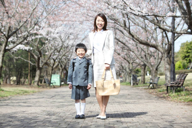 istock Cherry elementary school boys stand under a tree with his mother 674153976