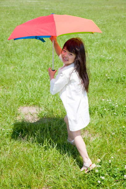 istock Using a parasol in a meadow, smiling girl 674159372