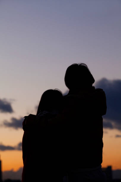 istock A couple shoulder to shoulder, watching the sunset silhouette 674159750