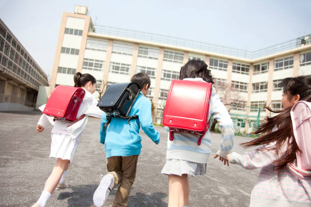 Rear view of the elementary school students go to school four Rear view of the elementary school students go to school four schoolyard photos stock pictures, royalty-free photos & images