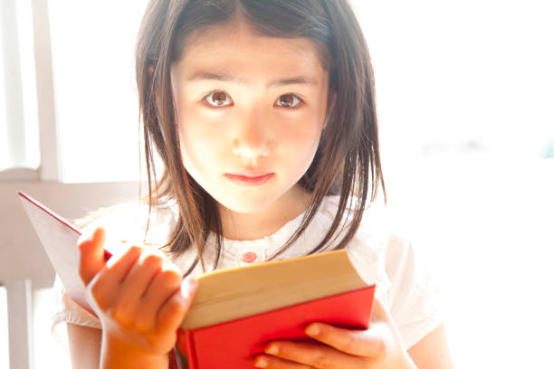 istock Elementary school girls reading books in the library 674170778