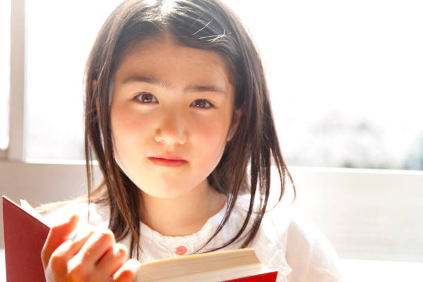 istock Elementary school girls reading books in the library 674170786