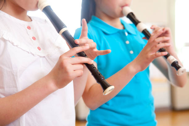 niñas de la escuela primaria soplan la flauta - recorder fotografías e imágenes de stock