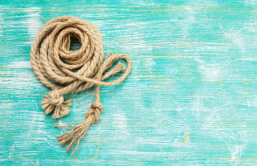 Ship rope knot on turquoise wooden background. Top view. Place for text.