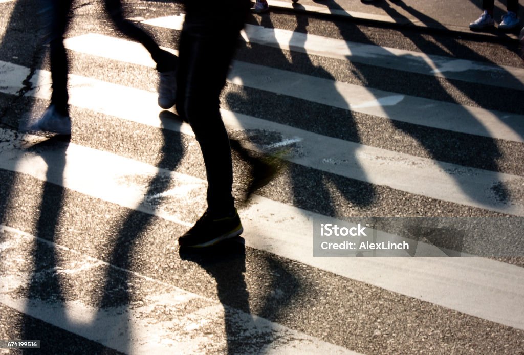 Blurry zebra crossing with  people silhouettes and  shadows Blurry zebra crossing with  people silhouettes and  shadows in sunset Back Lit Stock Photo