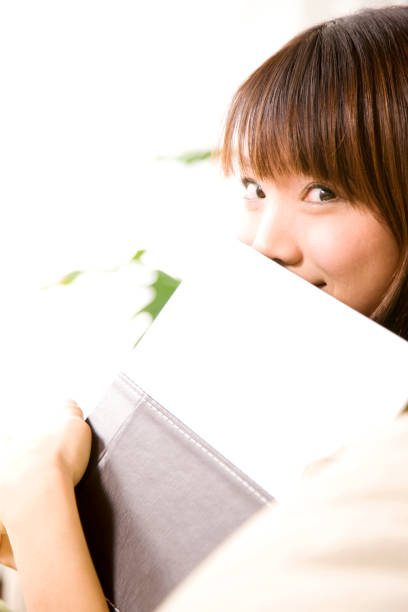 istock Women hide their faces in the book 674206528